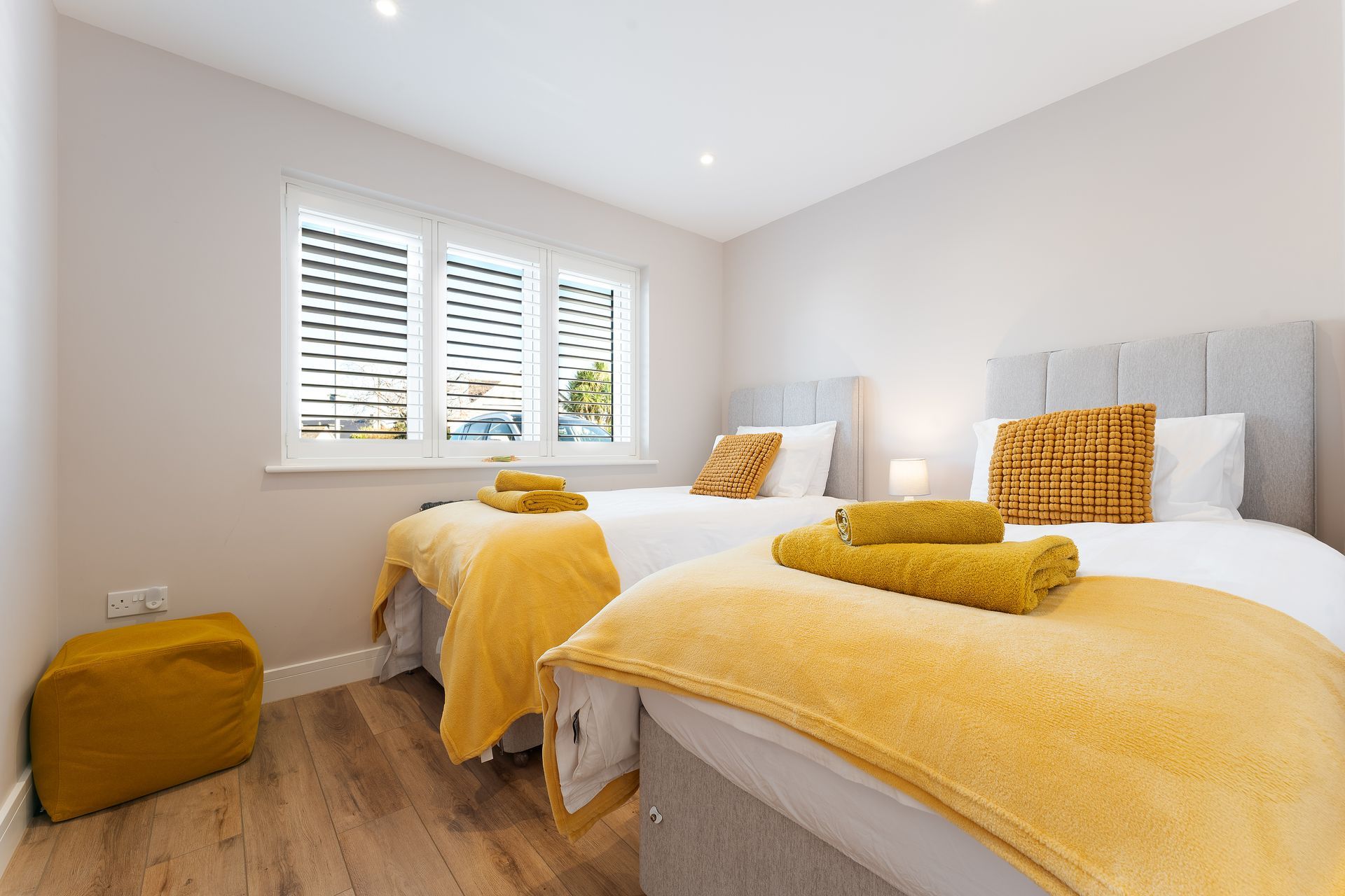 There are two beds in the room with yellow blankets.