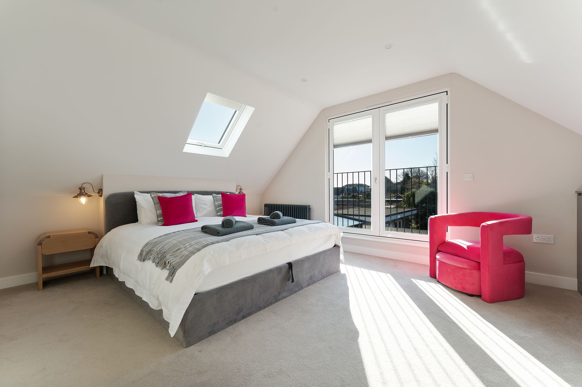 A bedroom with a king size bed and a pink chair.