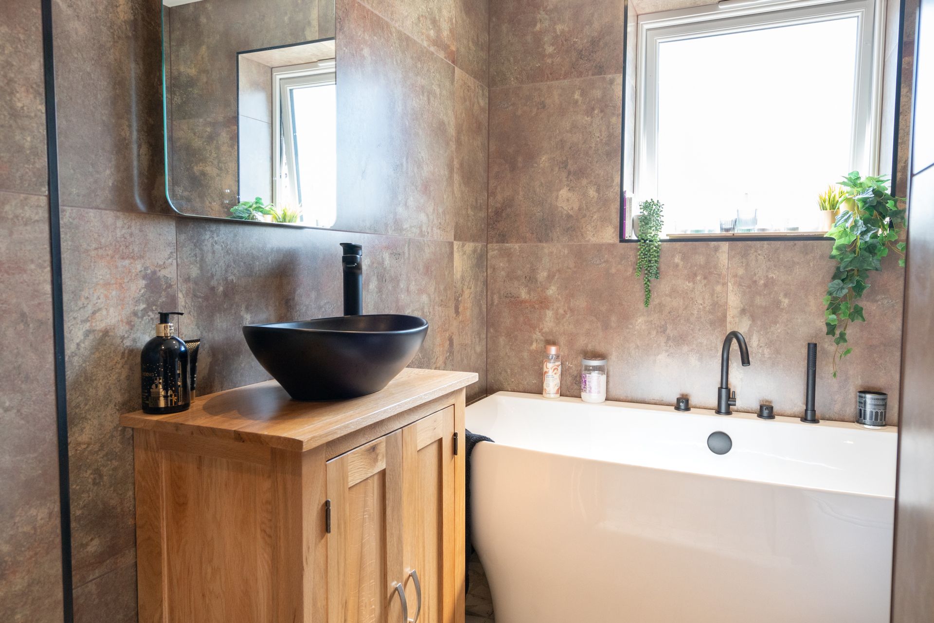 A bathroom with a sink , bathtub , mirror and window.
