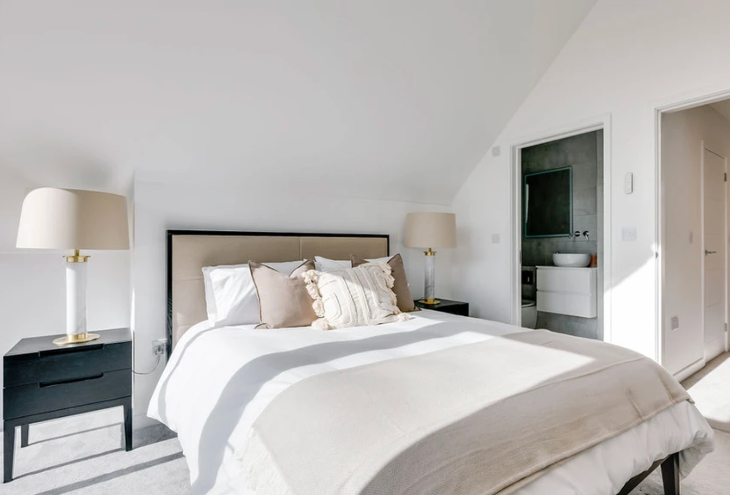 A bedroom with a bed , nightstand , lamps and a bathroom.