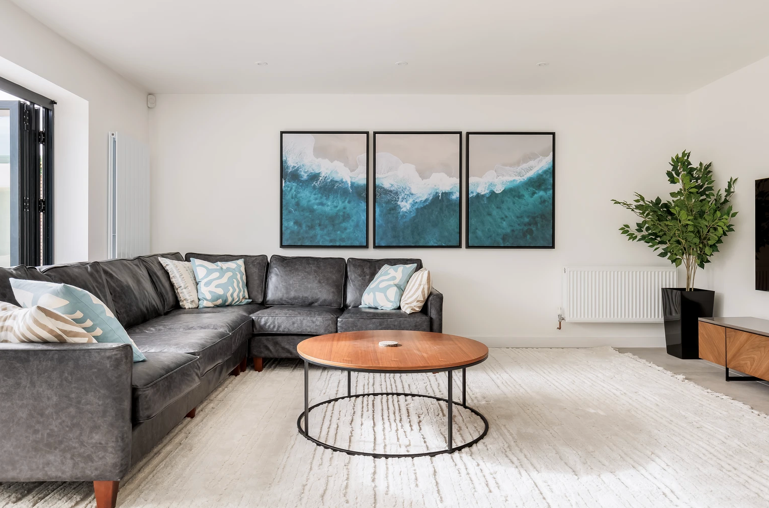 A living room with a couch , coffee table , and paintings on the wall.