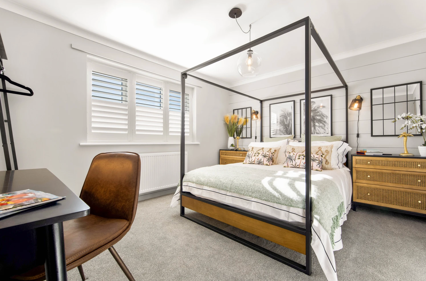 A bedroom with a four poster bed , desk and chair.