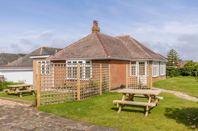 There are two picnic tables in front of a house.