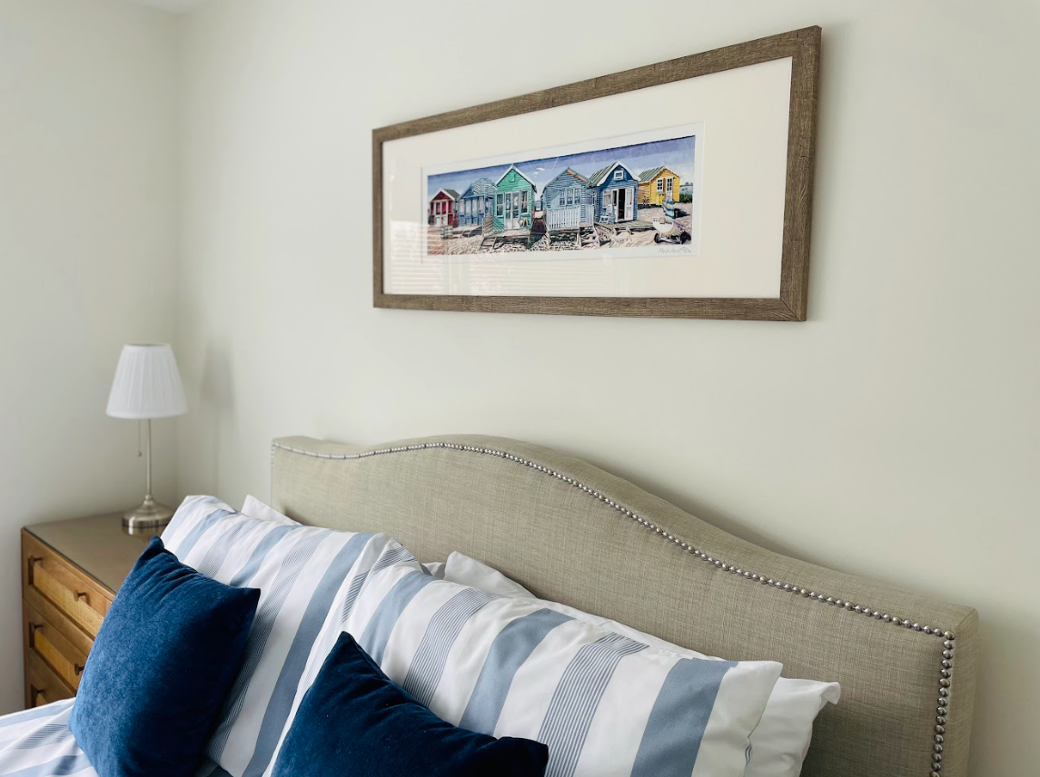 A bedroom with a bed and a picture on the wall above it
