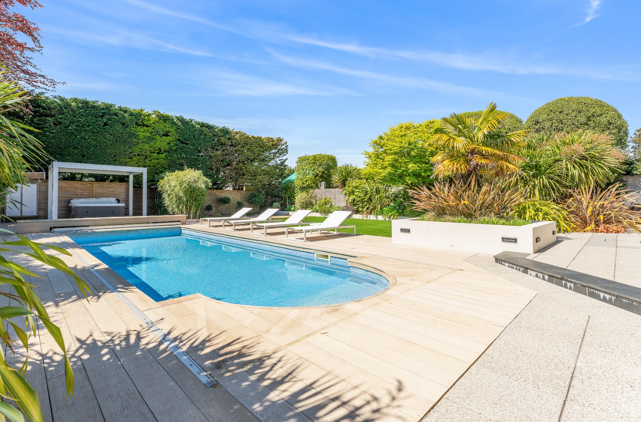 There is a large swimming pool in the middle of the backyard.
