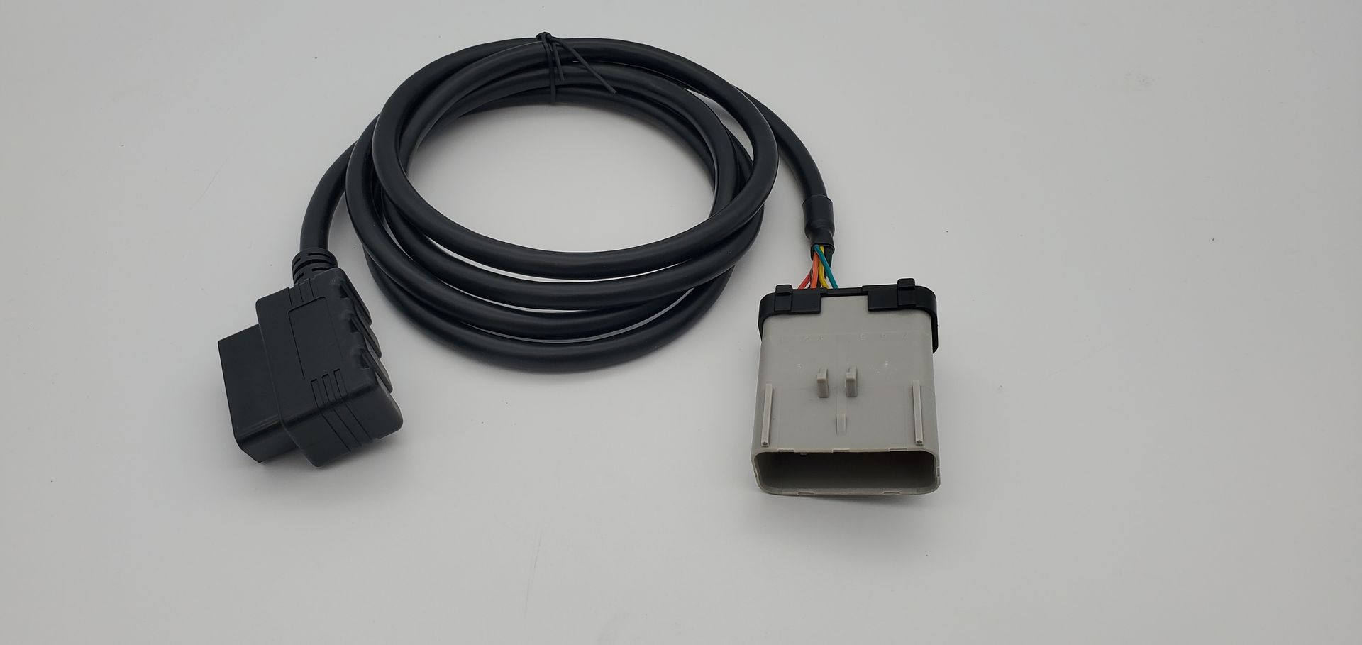 A black cable is connected to a small device on a white surface.