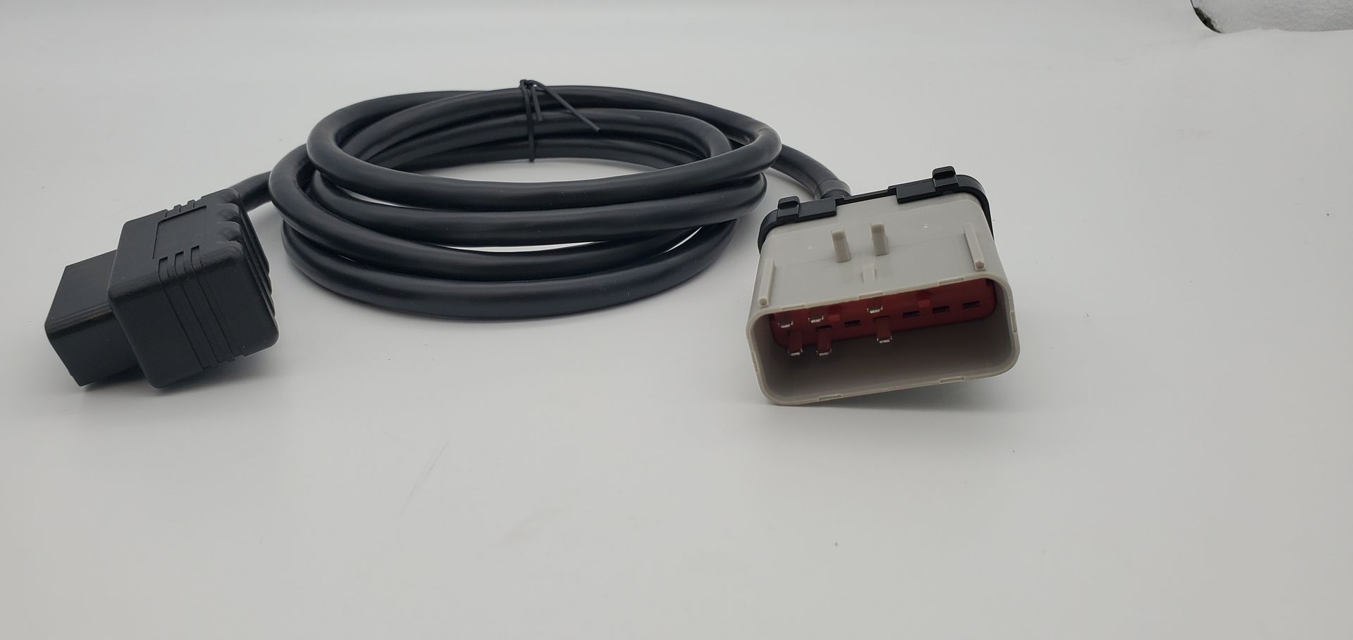 A cable with a connector attached to it is sitting on a white surface.