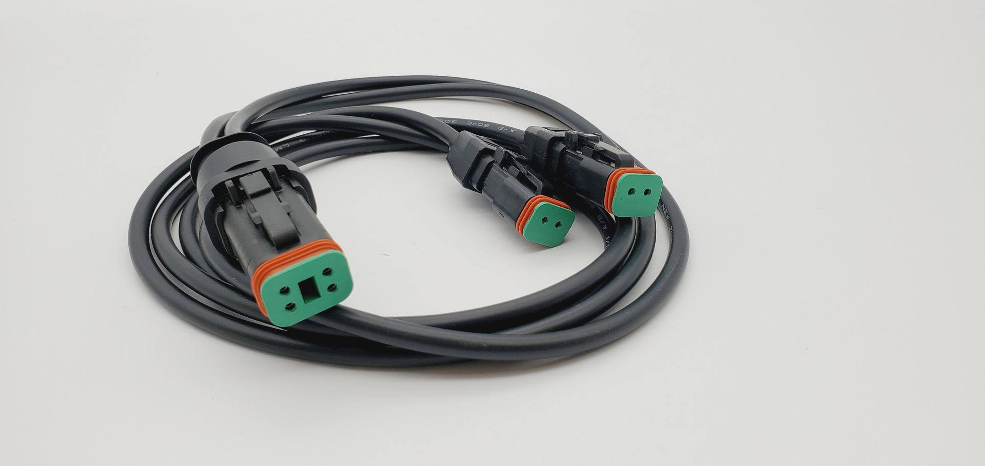 Coiled black cable with green-and-black connectors on a white background