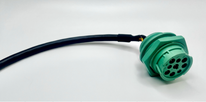 Green circular electrical connector attached to a black cable on a white background