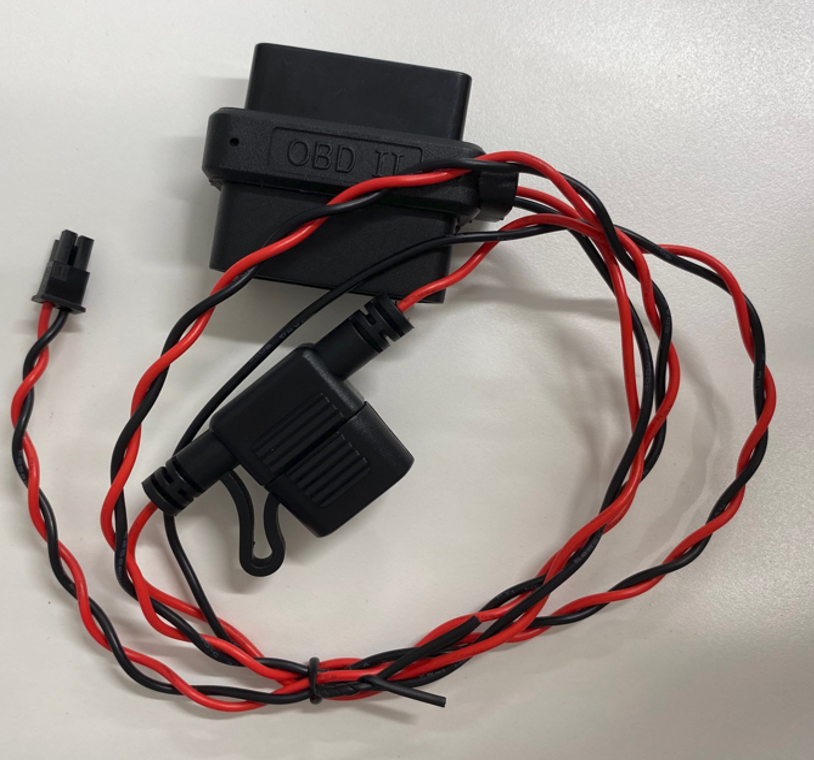 Black plastic electronic module with red-and-black twisted wires and a small connector on a white surface