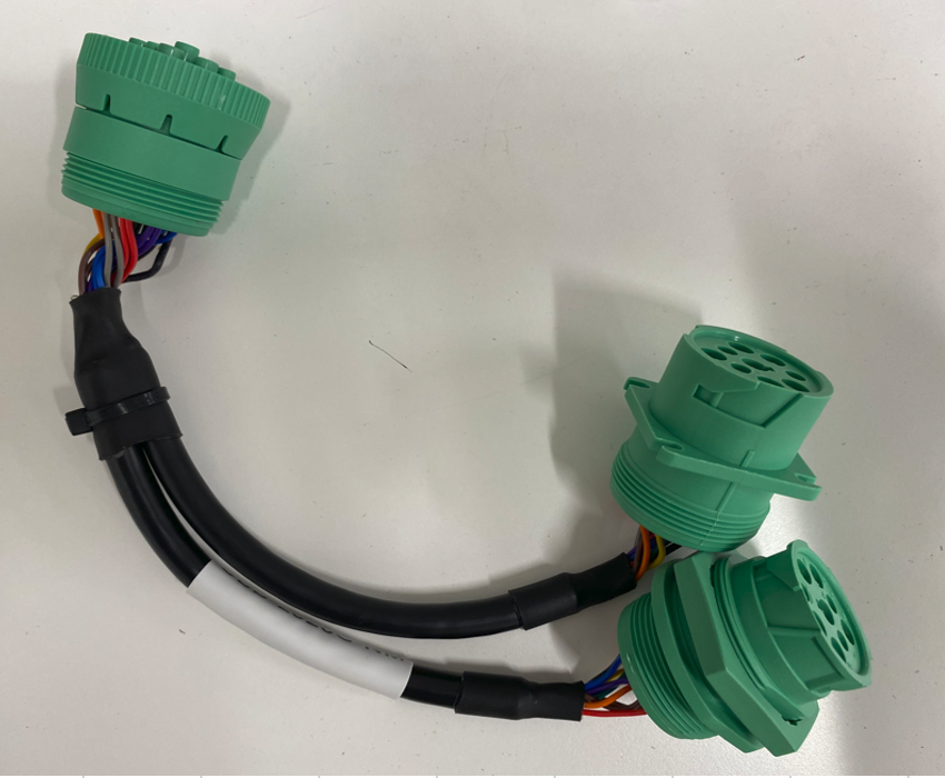 Black cable harness with three green electrical connectors on a white surface