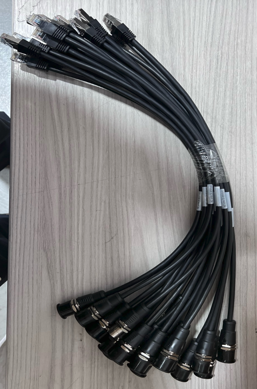 Bundle of black cable connectors arranged in a curved fan on a light wood surface