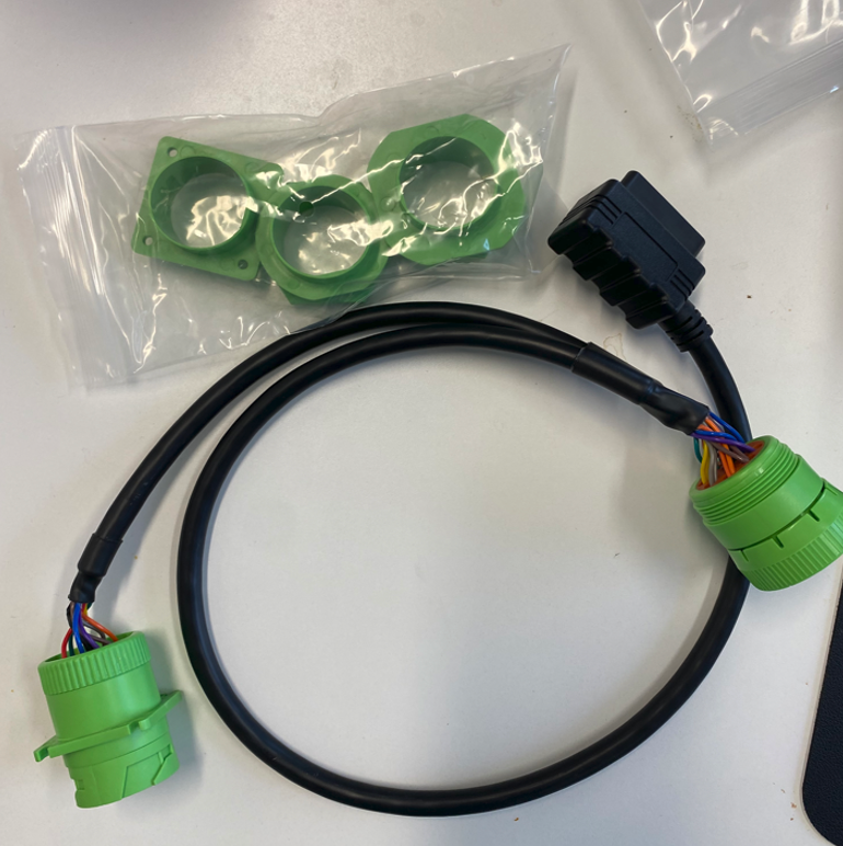 Black cable with green and blue electrical connectors on a white surface, with a bag of green caps above