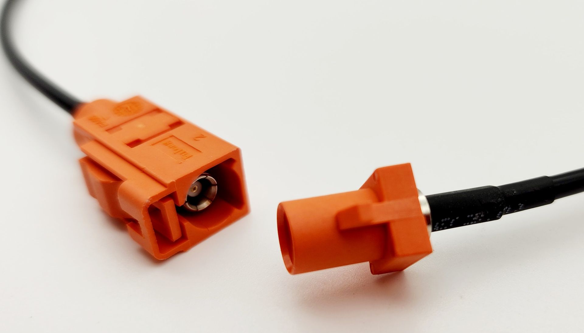 A close up of two orange connectors on a white surface.