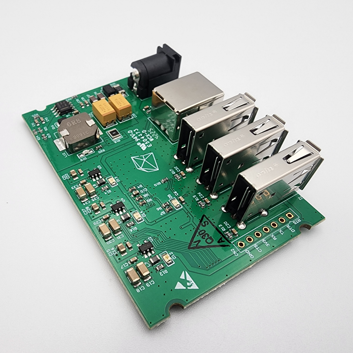 Green circuit board with stacked USB ports and a DC power jack on a white background