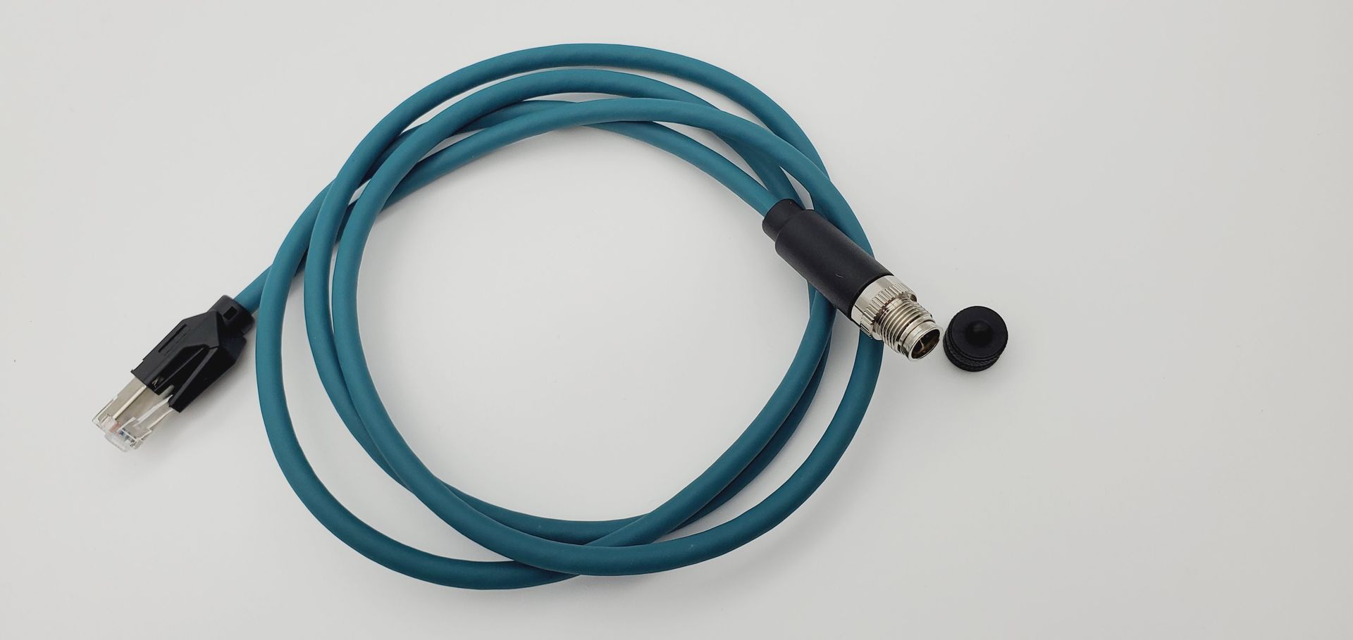 A blue cable with a black connector is sitting on a white surface.