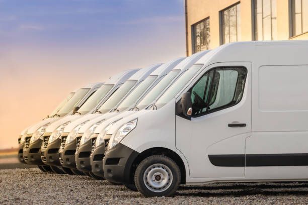 A row of white vans are parked in front of a building.