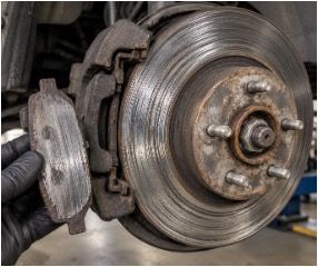 Close-up of a rusty car brake rotor and caliper assembly on a vehicle wheel hub