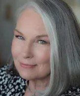 A woman with gray hair is smiling for the camera.