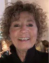 A woman with curly hair is smiling for the camera.