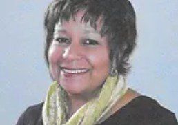 A woman wearing a black shirt and a green scarf is smiling.