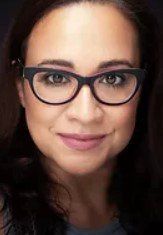 A close up of a woman wearing glasses and smiling.