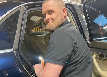 A man is sitting in the driver 's seat of a car.
