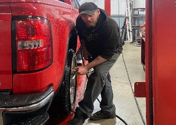A man is working on a red truck in a garage.