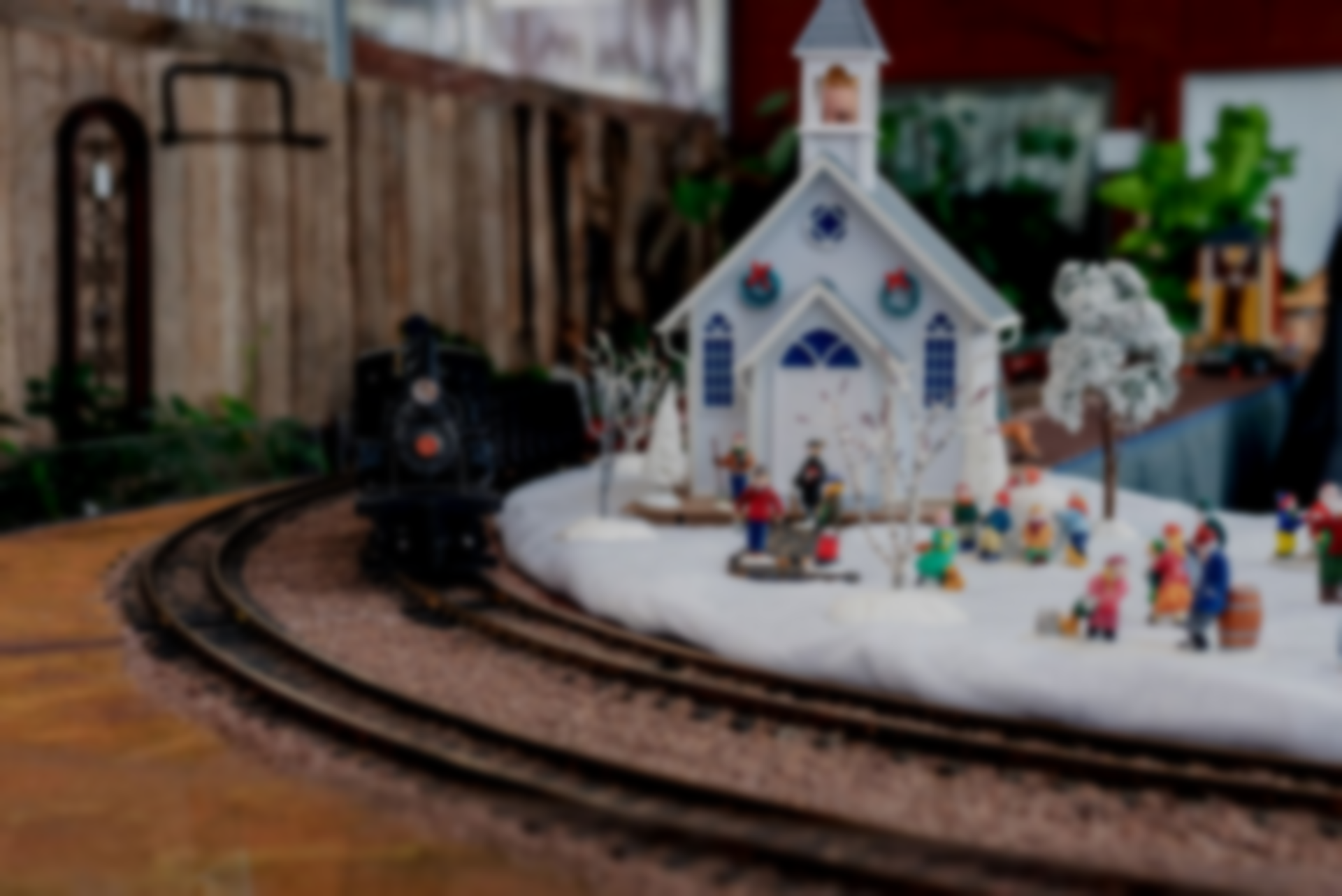 Model train passing a snowy church scene with miniature figures.
