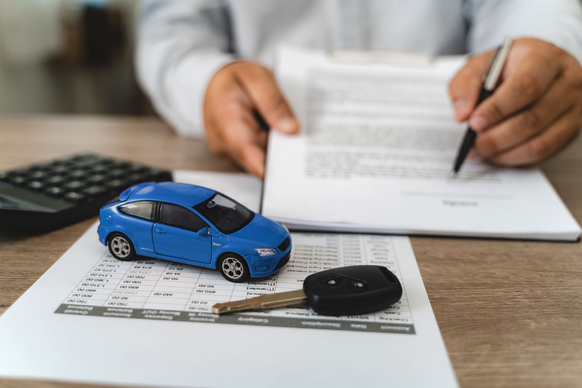 Toy car, keys, and calculator beside a signed auto loan agreement