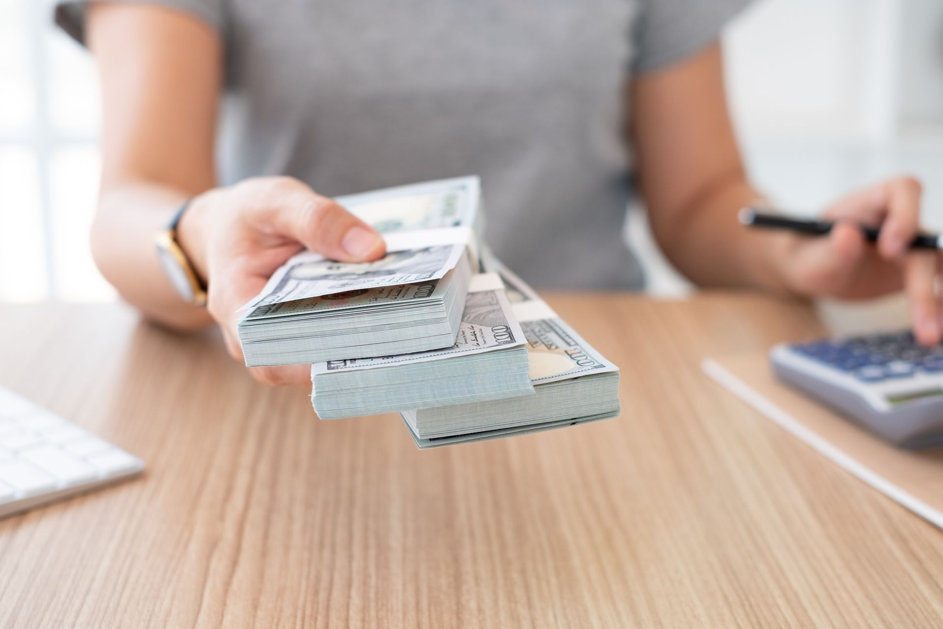 A woman has several stacks of dollars on her hand, presenting it to the camera.