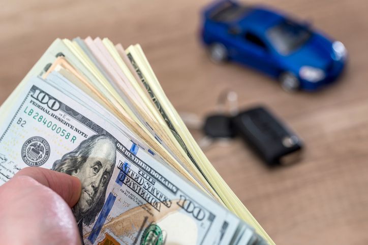 Man holding money, representing the affordable auto loan options available at Foti Financial Services in Gonzales, LA.