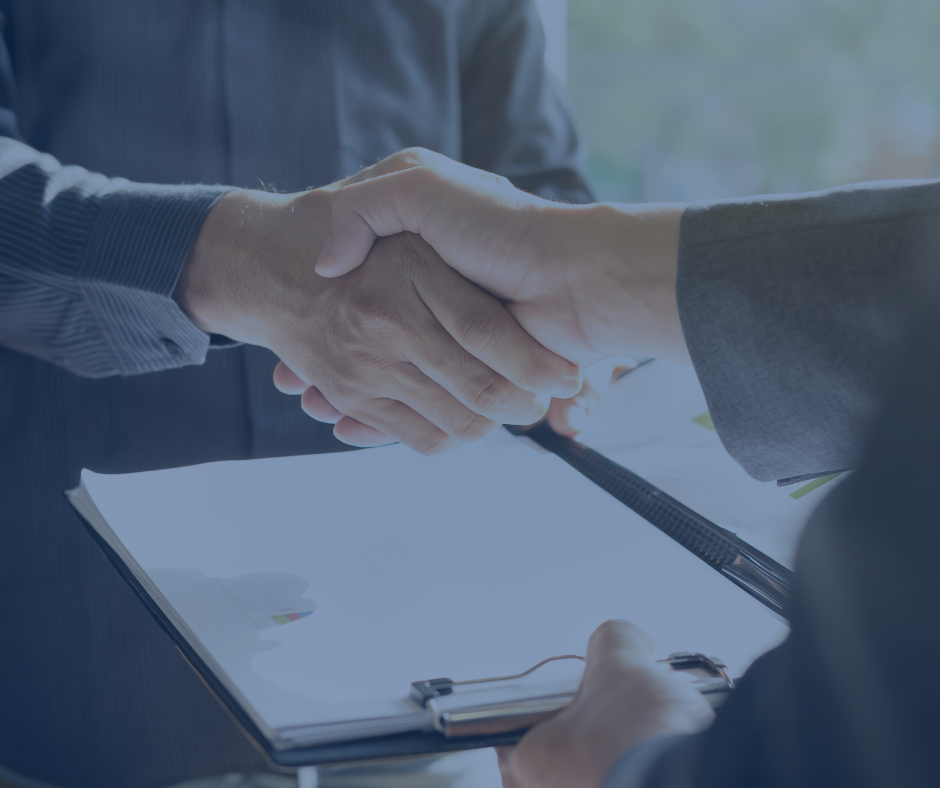 Two men are shaking hands over a clipboard.