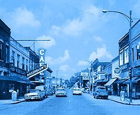 Cars are driving down a street with a sign that says car
