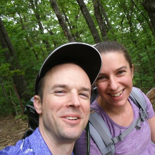A man and a woman are taking a selfie in the woods