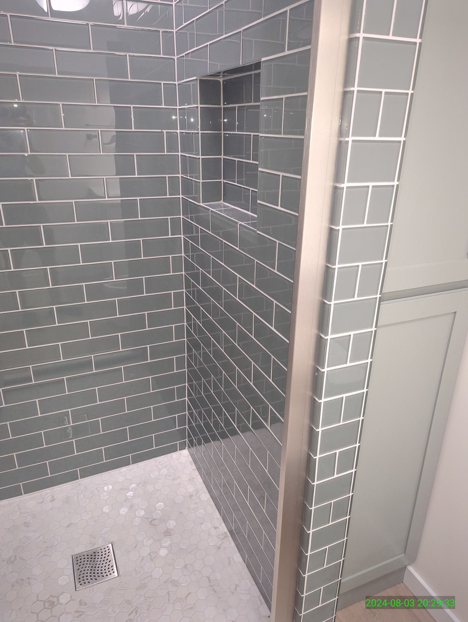 A bathroom with a walk in shower with gray tiles