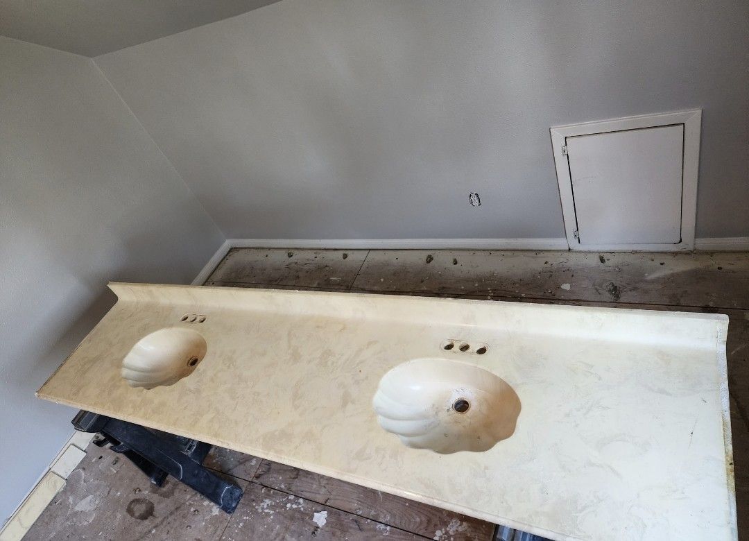 Bathroom vanity countertop with two sink cutouts and a backsplash under renovation