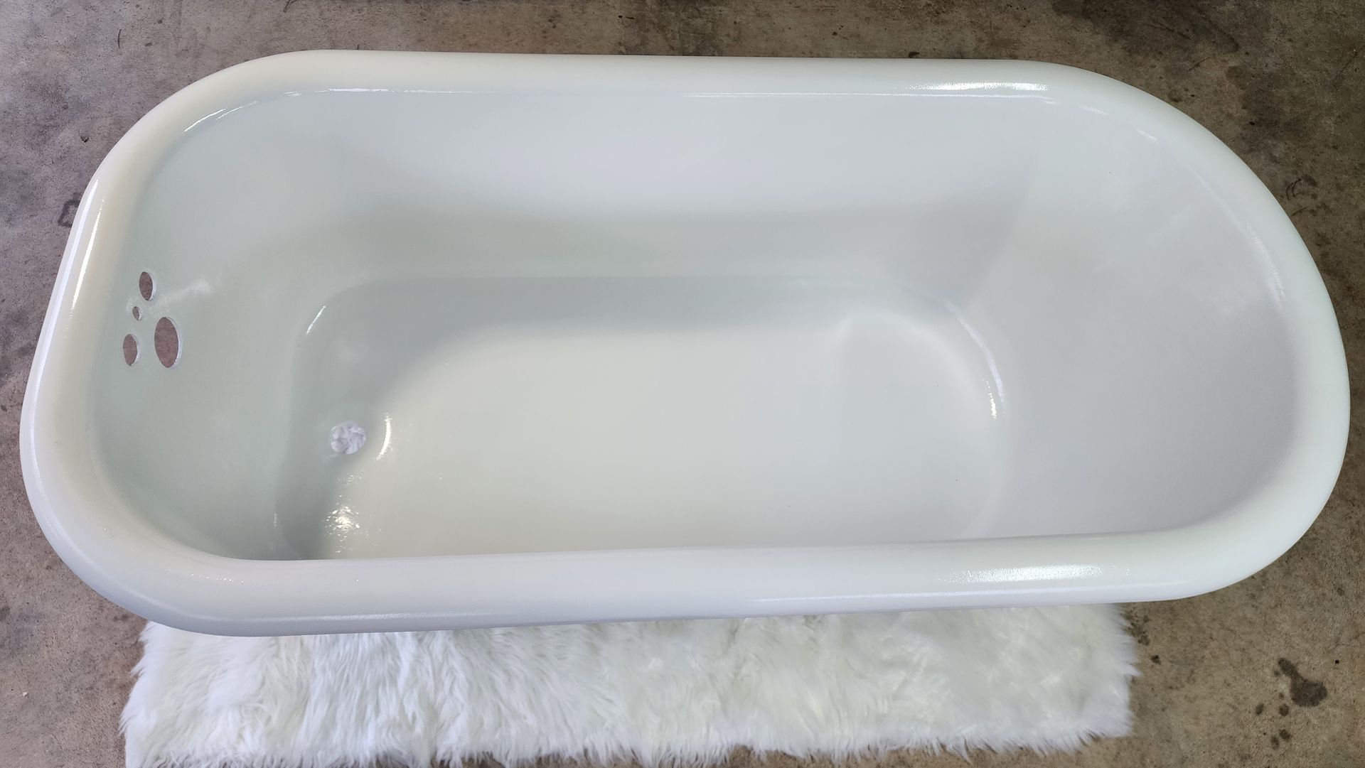White bathtub sitting on a rug on a concrete floor