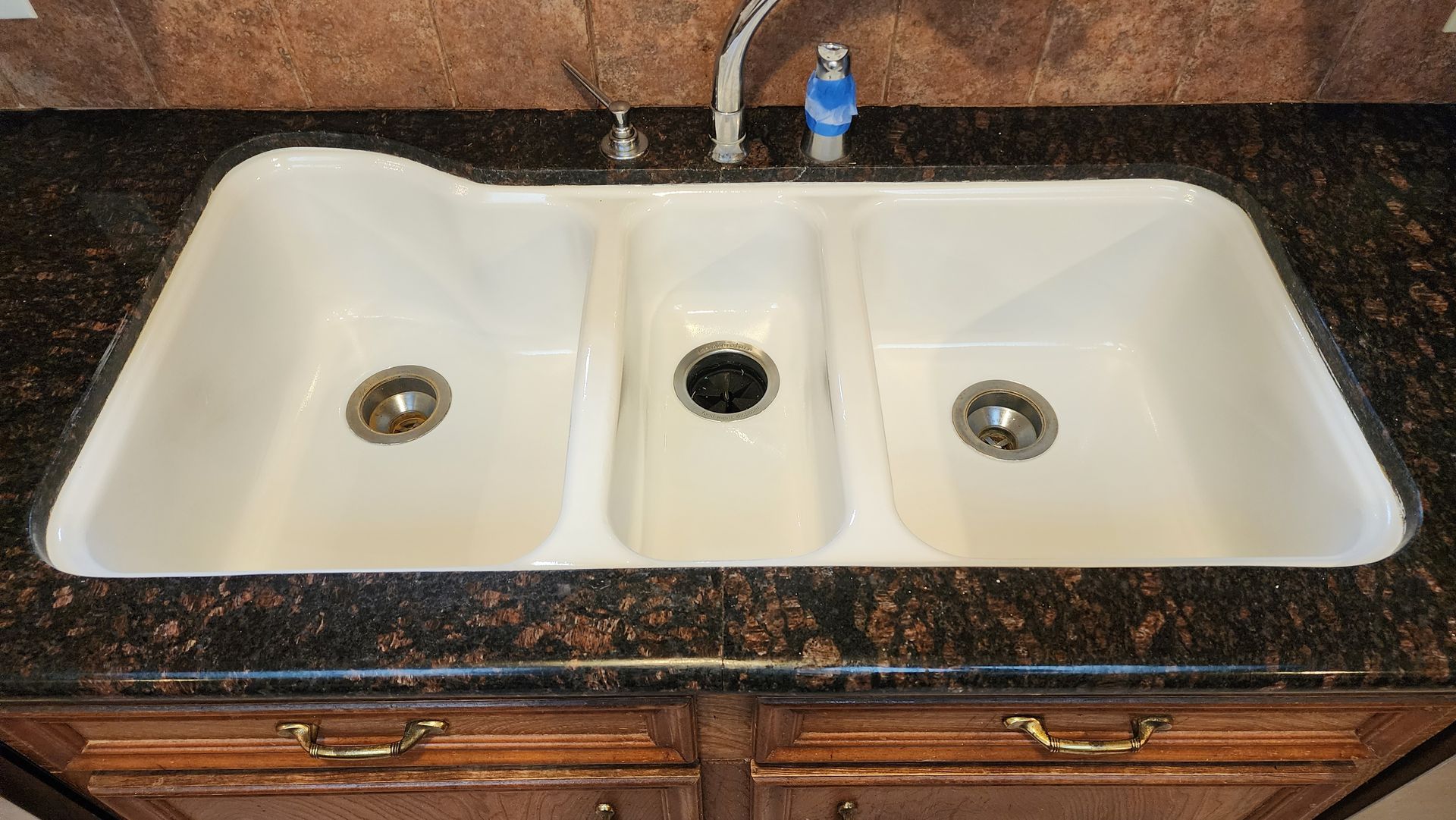 Double white bathroom sink with dark granite countertop and faucet.