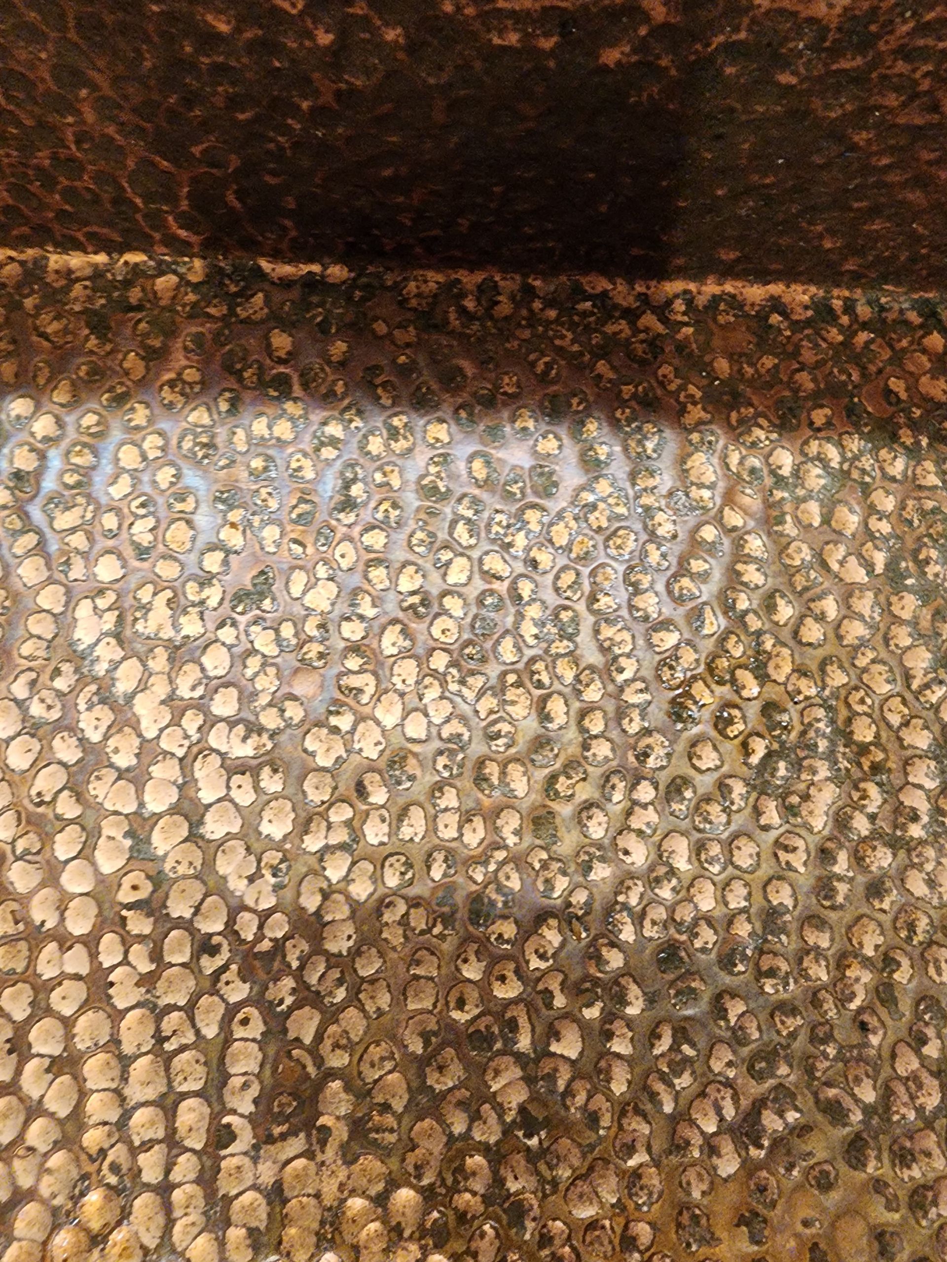 Close-up of a textured brown and tan stone or pebble surface with a dark shadow across the top.