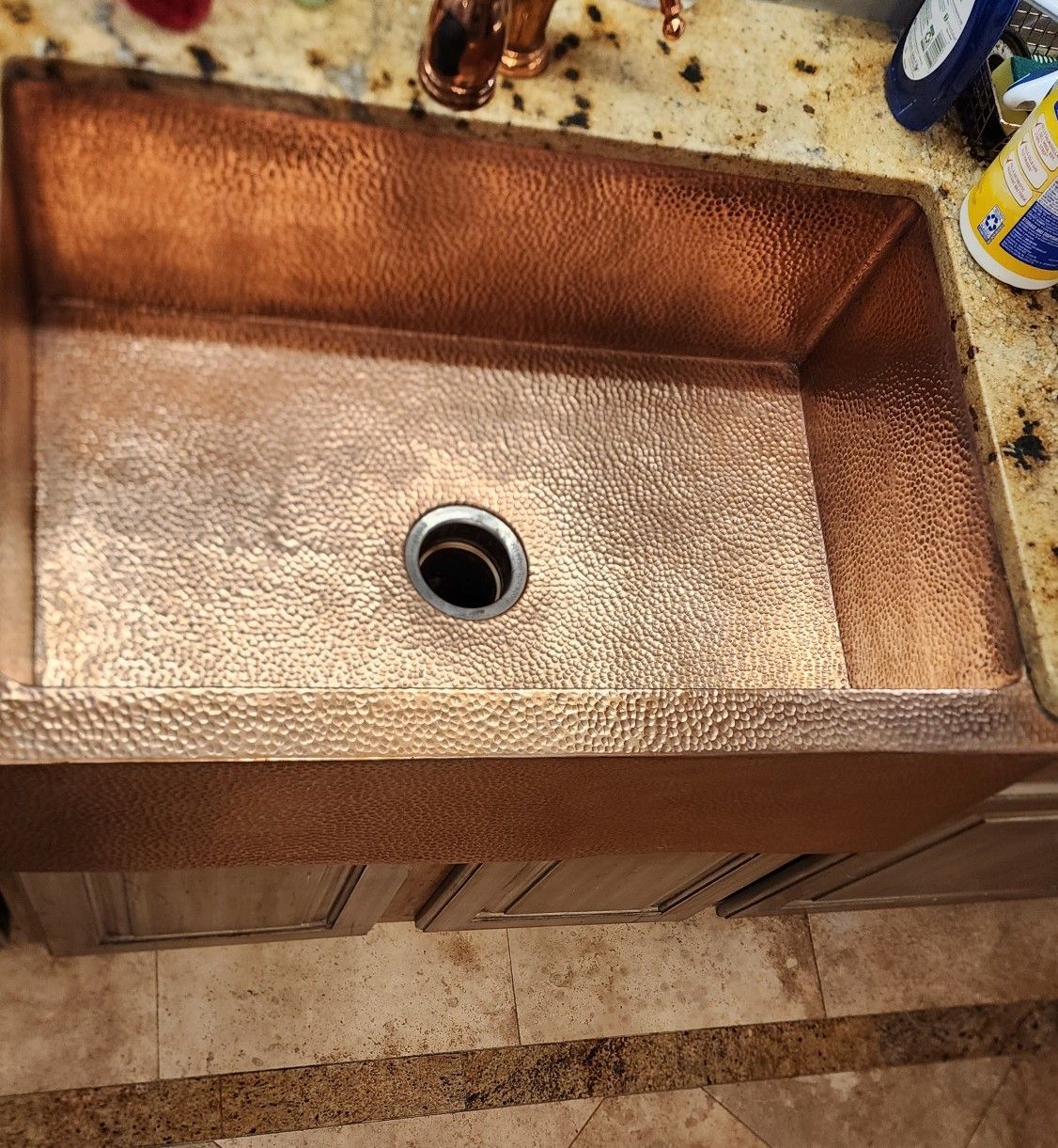 Copper farmhouse sink with a central drain in a granite countertop