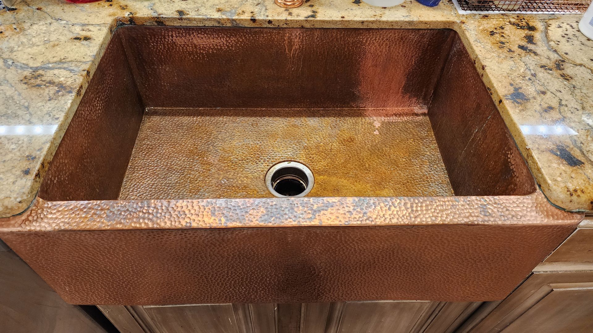 Rusty copper farmhouse sink on a countertop with a drain in the center