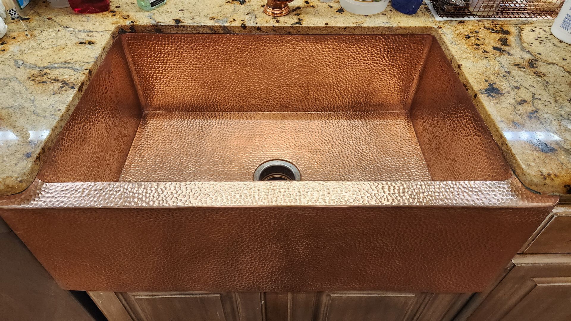 Rust-colored copper kitchen sink with a central drain set into a countertop.