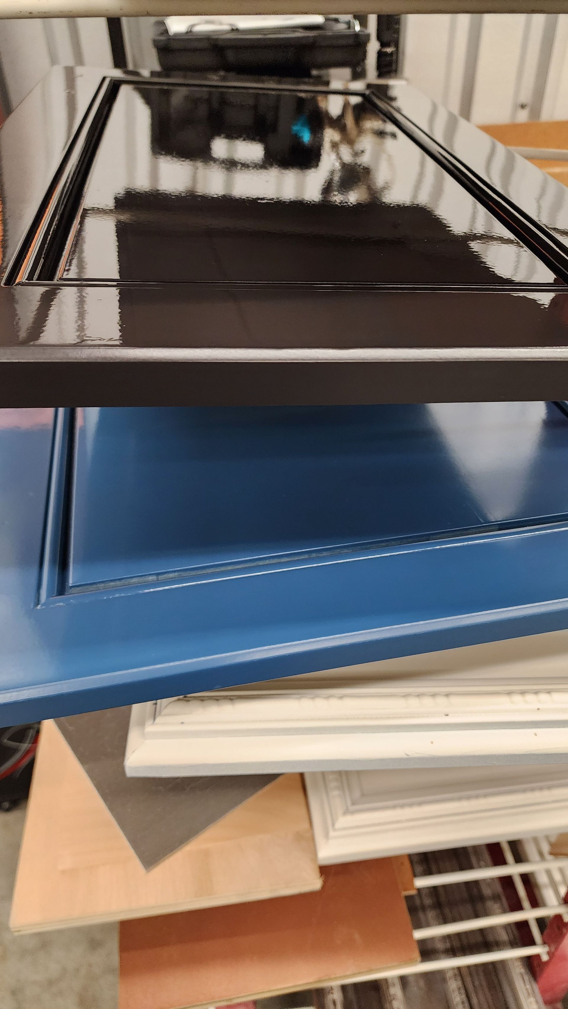 Stacked metal shelves holding blue, black, and beige trays in a storage area.