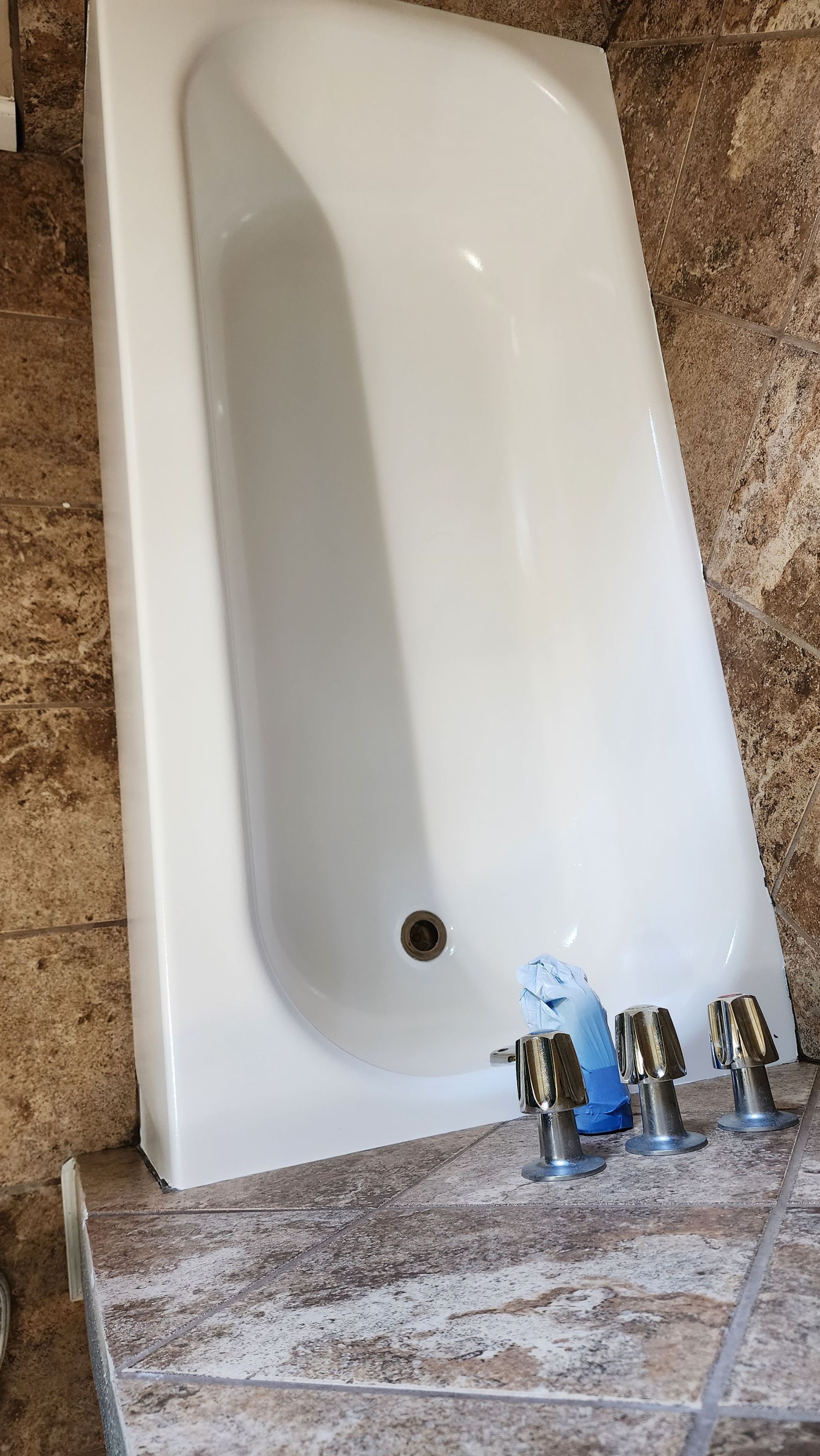 White wall-mounted sink or urinal with faucet fixtures on a stone or tile floor.