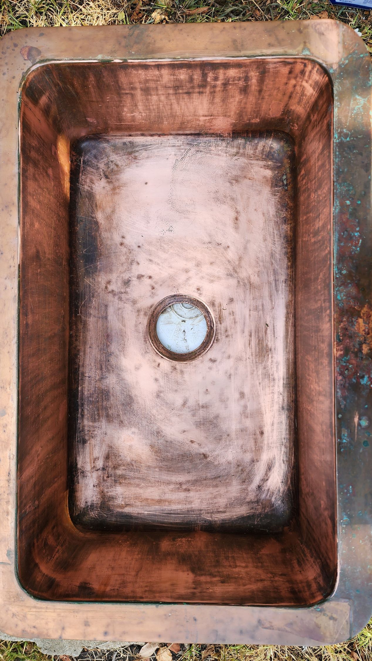 Rust-colored rectangular sink basin with a central drain, viewed from above.