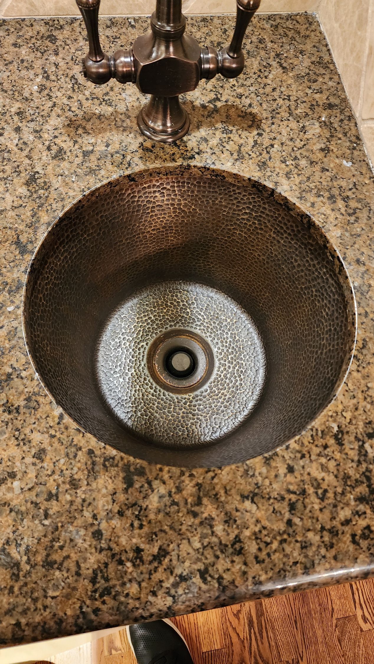 Bathroom sink with a dark stone countertop and bronze faucet