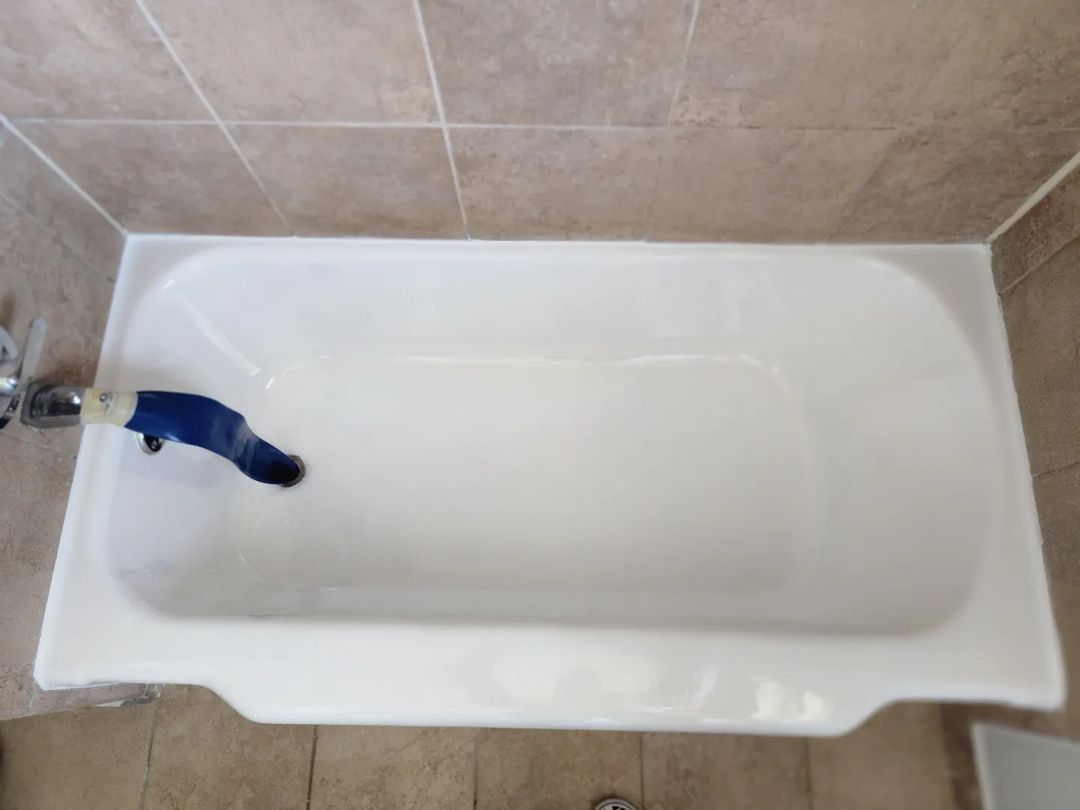 White bathtub with a blue faucet in a tiled bathroom