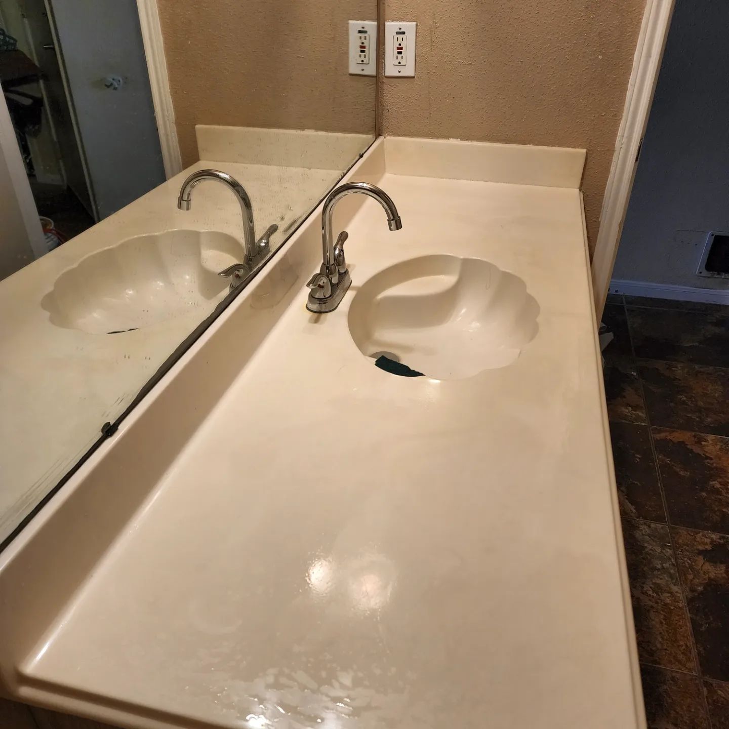 Bathroom vanity with beige countertop, single sink, and chrome faucet beside a wall mirror.
