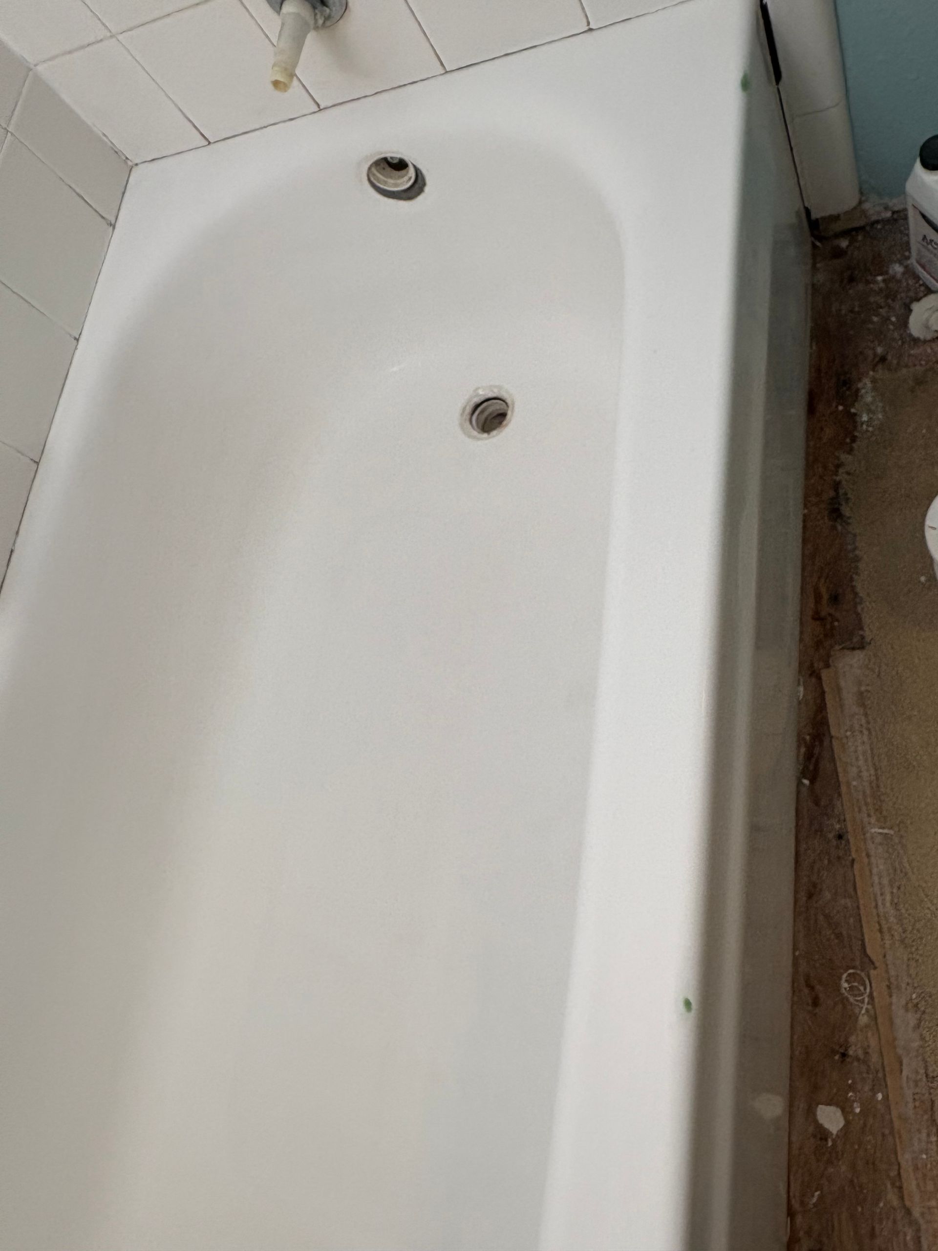 White bathtub against tiled wall with two metal fixtures visible.